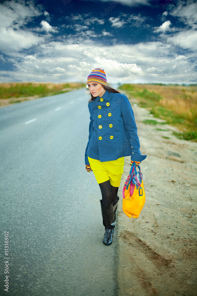 Obraz premium The young fashionable girl walking road with a bag
