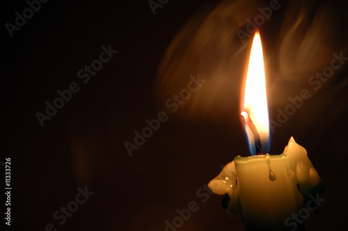 Smoke and candle flame burning in the darkness