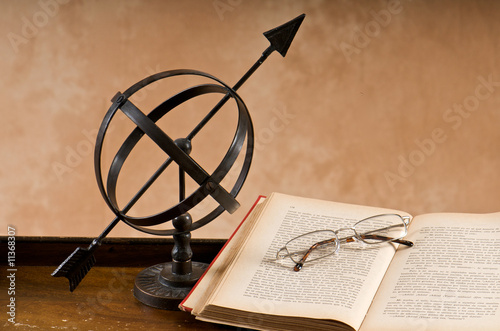 Old armillary with book and eyeglasses. photo