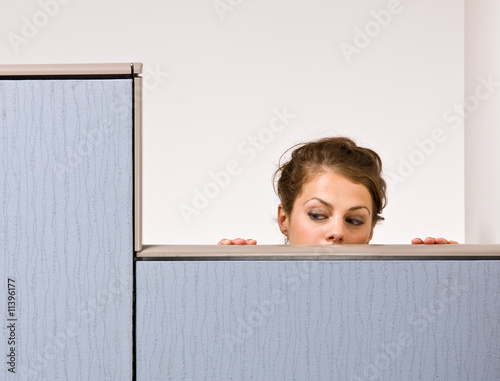 Businesswoman peering over cubicle wall