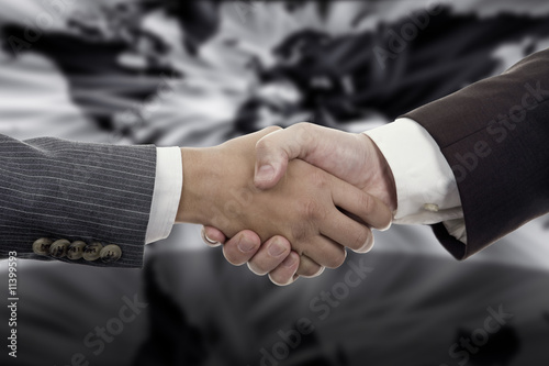 Business Hand shaking on a word map background