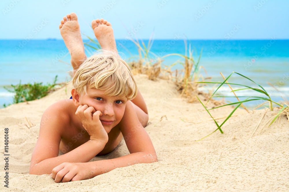 Мальчик на девочке на пляже фото Young blond boy lying on the beach фотография Stock Adobe Stock