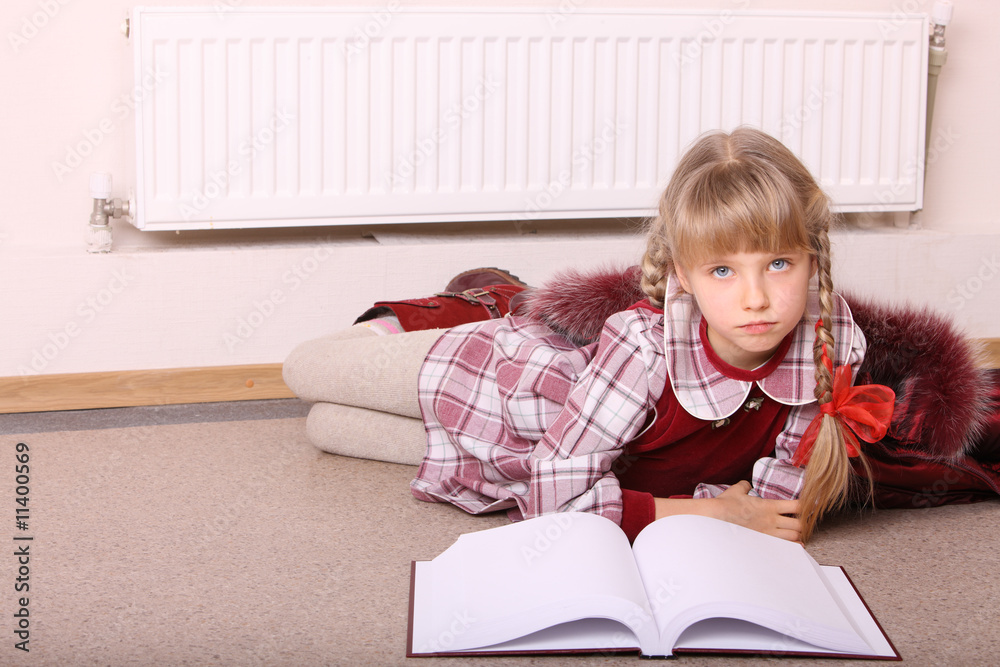 Girl lie near radiator with book. Cold crisis.