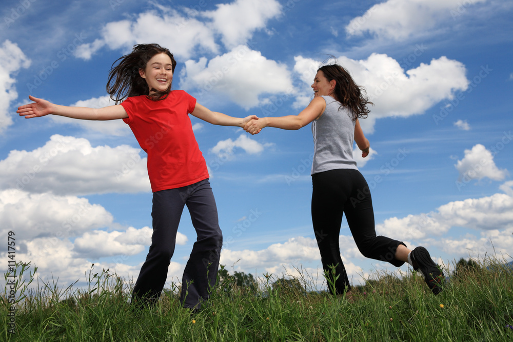 Mum and running, jumping on green meadow against blue sky Mum and running, jumping on green meadow against blue sky