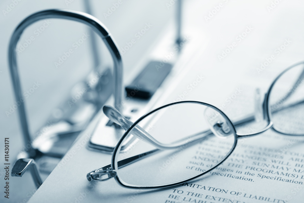 open binder and glasses over document toned blue open binder and glasses over document toned blue