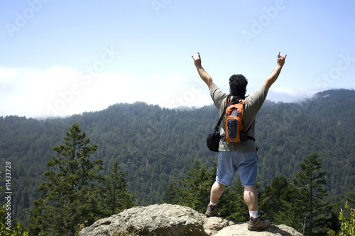 Hiker Shows Sign of Victory on Top of Mountain Peak