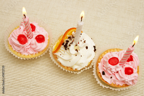 Three birthday cupcakes with candles.