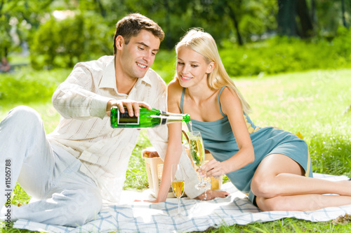 Young happy couple celebrating with champagne at picnic
