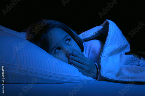 cute girl with eyes open and hand over mouth in bed