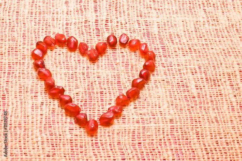 bright red pomegranate heart on textile background