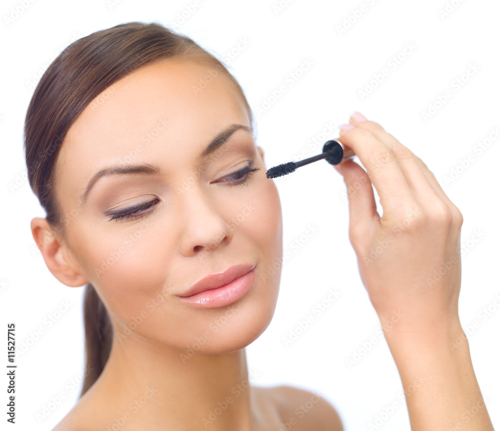 Portrait of beautiful woman doing makeup, on white
