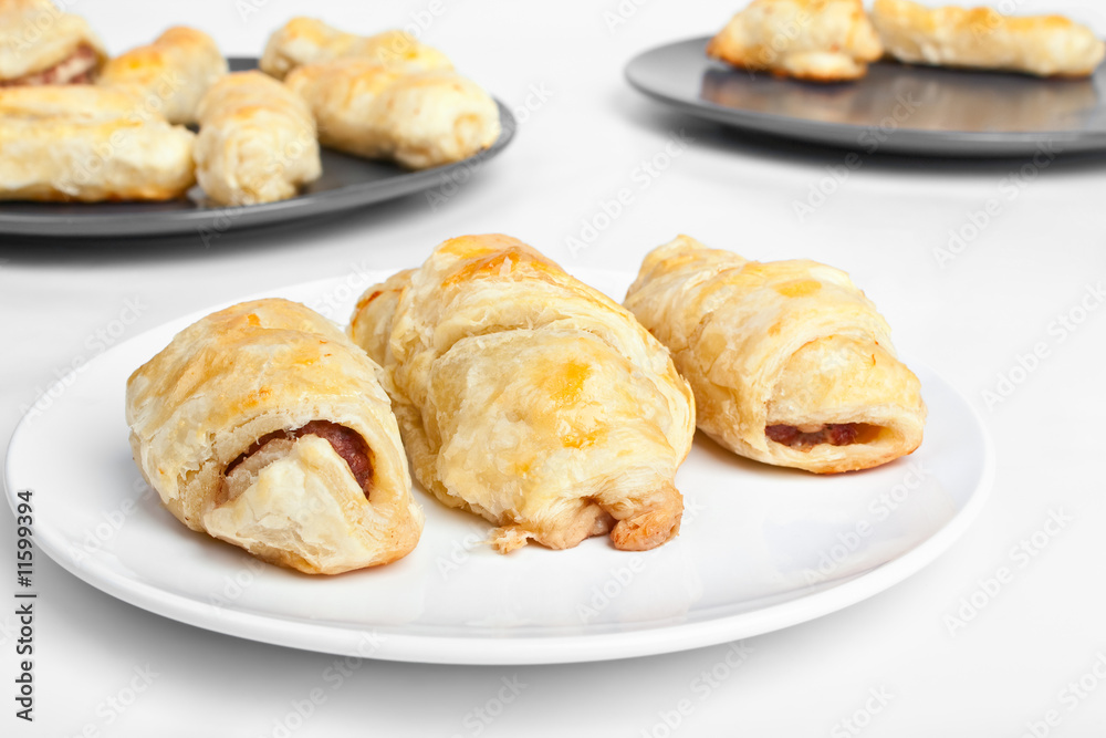 three sausage rolls with more rolls at the background three sausage rolls with more rolls at the background