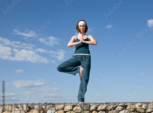 Woman making Yoga exercises in top of a stone wall