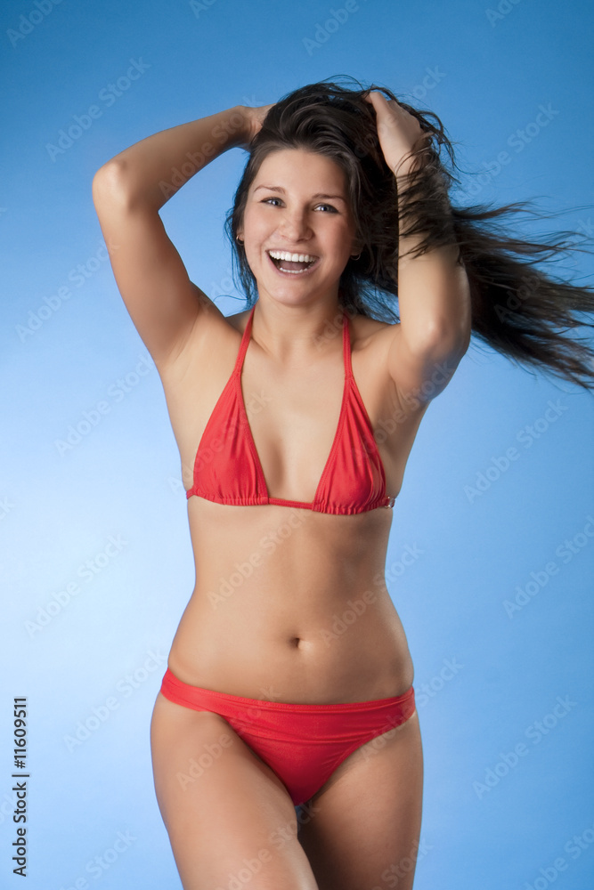 Obraz premium Bright brunette in a red bathing suit on a blue background