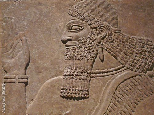 Ancient Assyrian wall carving of a man showing his head and hand