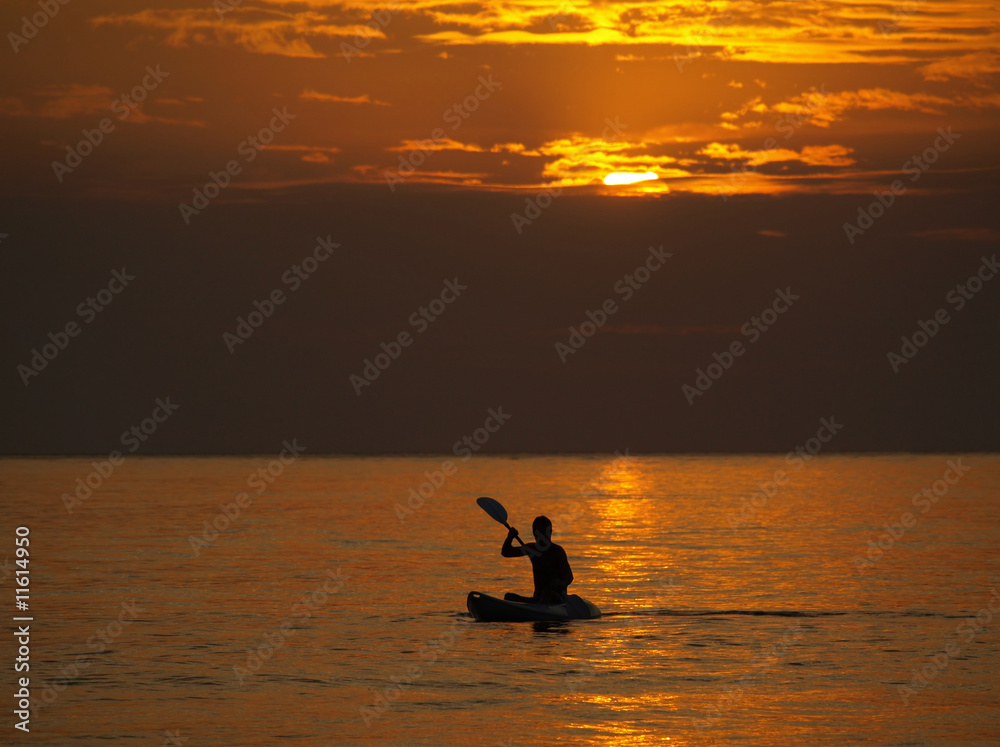 Silhouette of man kayaking at sunset