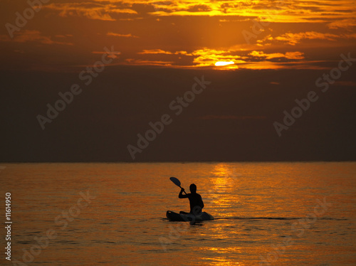 Silhouette of man kayaking at sunset