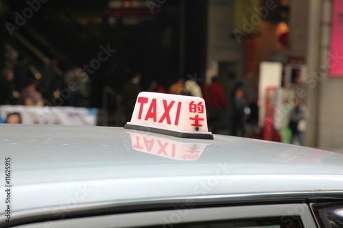 A lit Hong Kong taxi sign with english and chinese writing