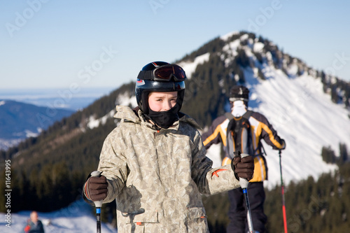young skier wearing helmet with mountain background