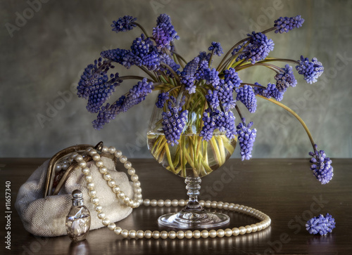 Still-life with a bouquet , a handbag, pearls and spirits