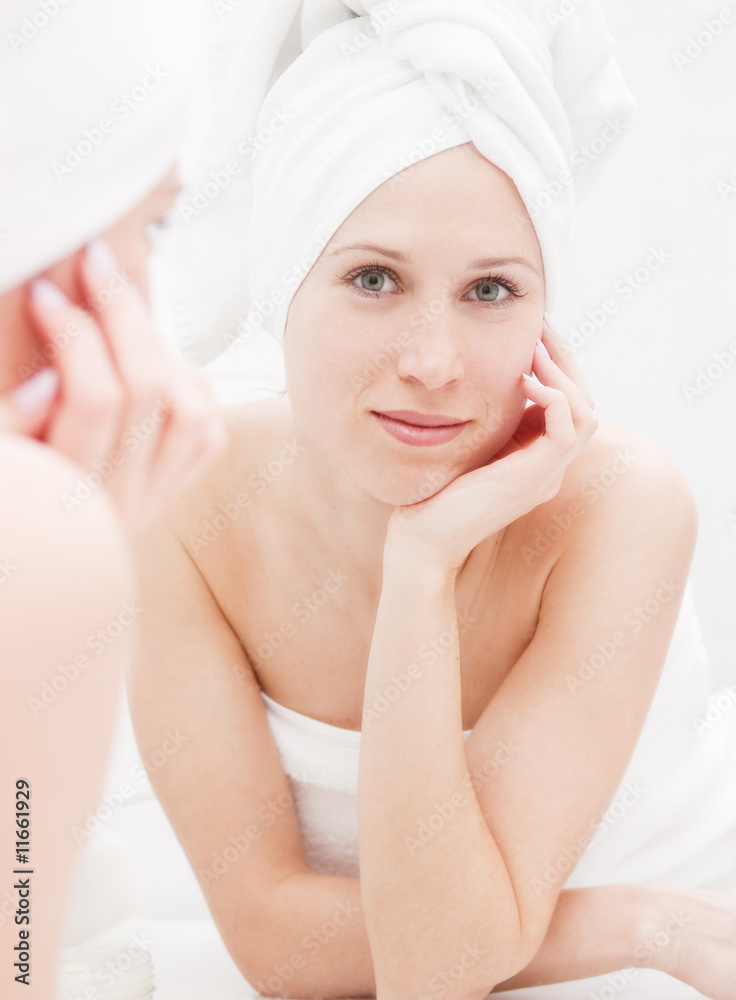 young woman after shower looking at her reflection young woman after shower looking at her reflection