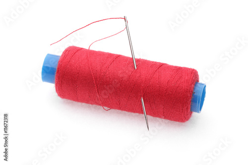 The coil of red threads with needle on white background