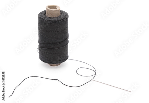 The coil of black threads with needle on white background