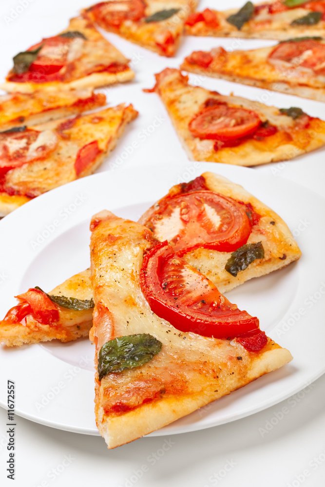 two slices of pizza on a plate and other pieces at the back two slices of pizza on a plate and other pieces at the back