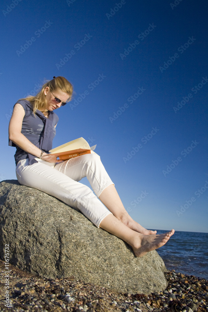 Frau am Strand liest ein Buch