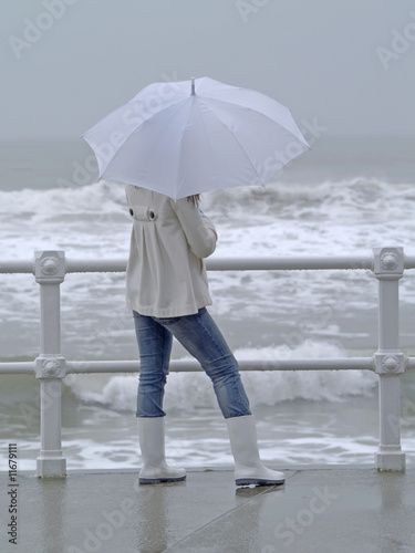 Chica con paraguas mirando al mar