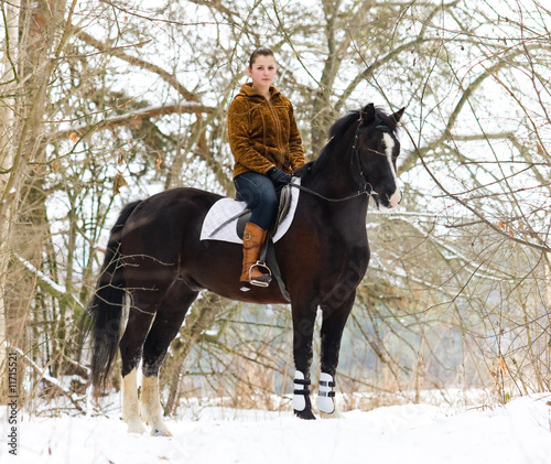 The girl is riding a horse in a winter forest