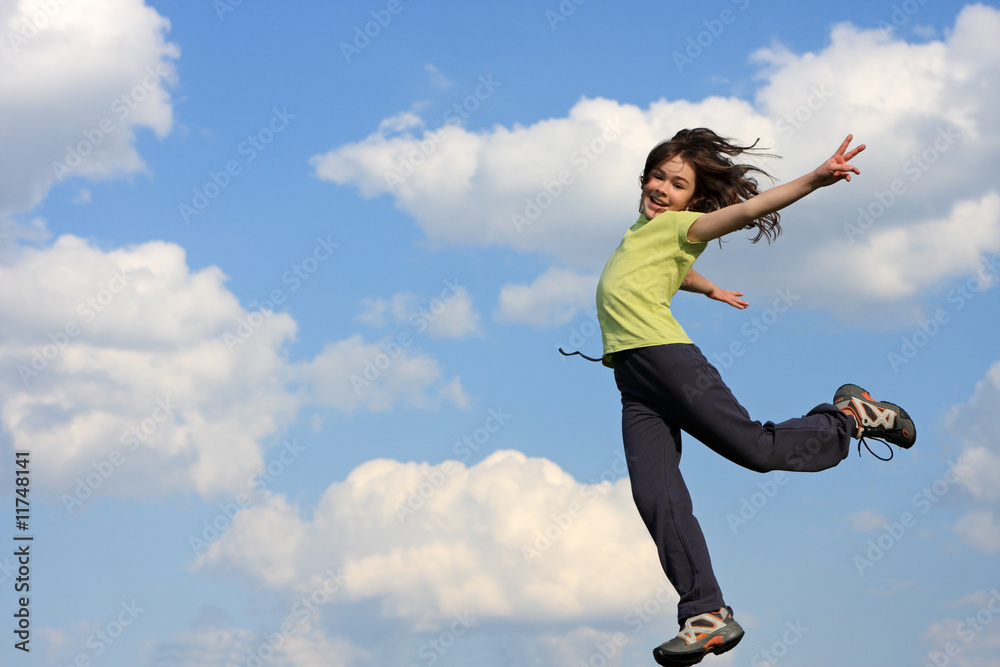 Kid running, jumping on green meadow against blue sky Kid running, jumping on green meadow against blue sky