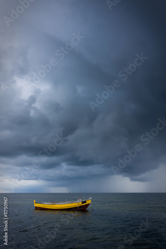 Yellow fishing boat in a sea against dramatci sky