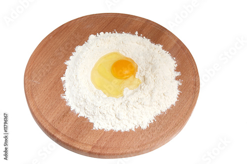 Flour and eggs on wooden board.