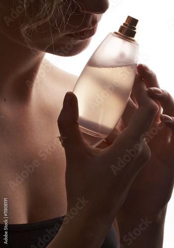 sensual woman smelling perfume, golden perfume bottle