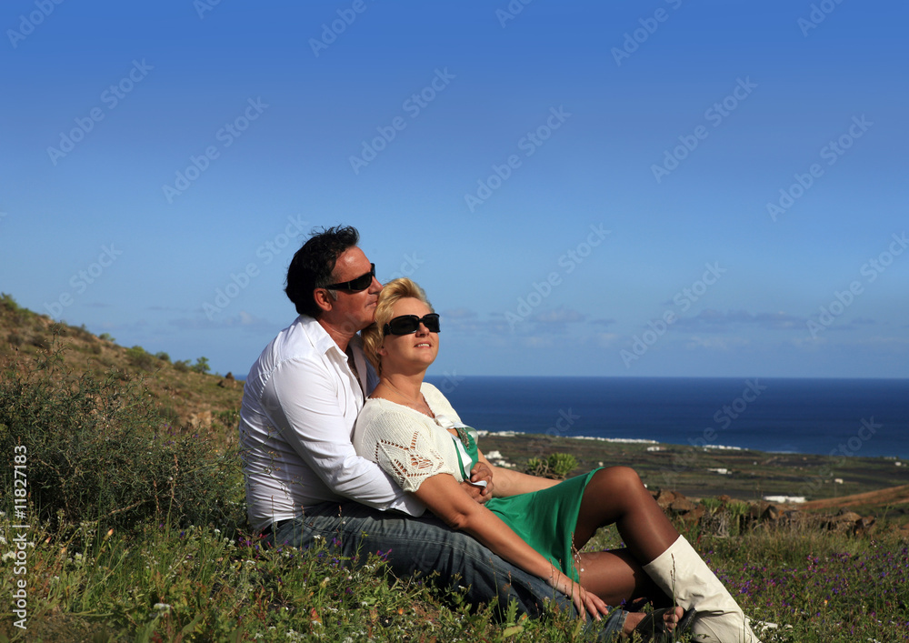 Couple sitting outdoors holding flower smiling