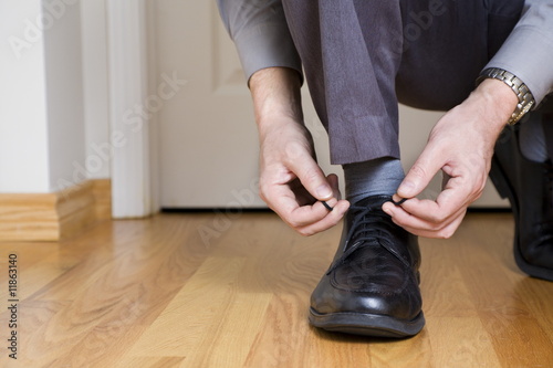 Businessman is tying shoes before leaving for work