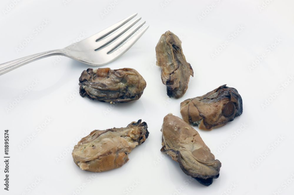 Five delectable smoked oysters on a plate with a fork. Five delectable smoked oysters on a plate with a fork.