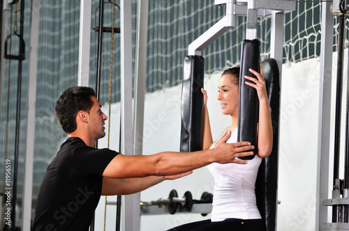 woman in the fitness gim working out with personal trainer photo