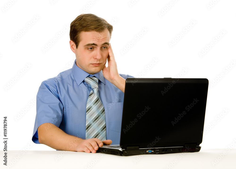 Tired young businessman working on a laptop. Isolated on white. Tired young businessman working on a laptop. Isolated on white.