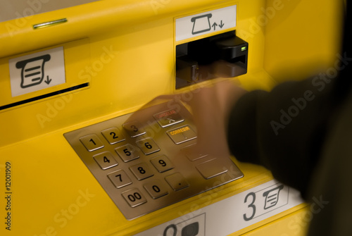 A hand touching the keboard of the ATM