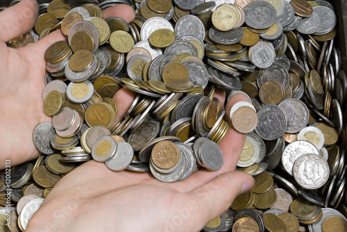 Hands in the pile of different white, red and yellow coins