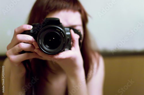 Jeune femme prenant une photo avec un reflex numérique en mains