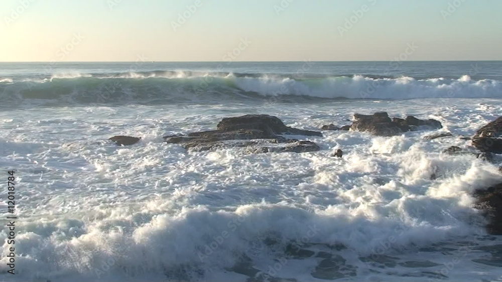 Agitated sea waves against rocks in the beach