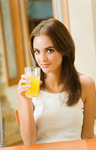 Portrait of young woman drinking orange juice at home