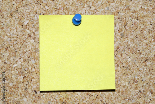 Blank yellow sticky note on corkboard