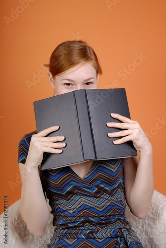 The woman hides the face behind the book