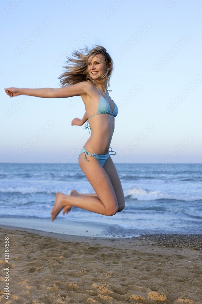 Beautiful blond girl jumping on the beach Beautiful blond girl jumping on the beach