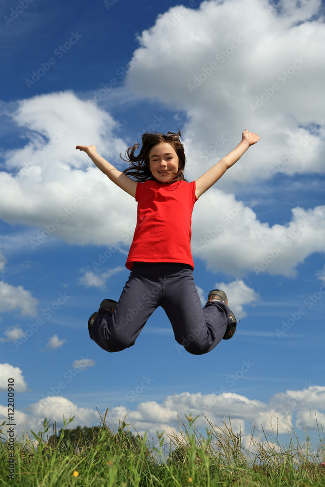 Kid running, jumping on green meadow against blue sky Kid running, jumping on green meadow against blue sky