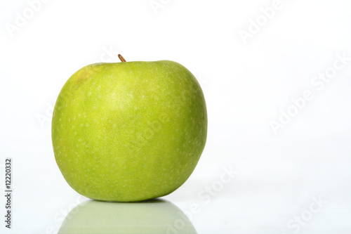 Juicy wet green apple on a table with isolated white background